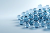 Transparent blue glass spheres or marbles arranged in rows on light background with soft focus and selective depth of field creating artistic composition.