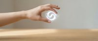 Hand holding glowing white swirl symbol above wooden surface representing energy, spirituality, and digital transformation concepts for business presentations.
