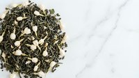 Green tea blend with almond slices on marble surface, isolated for culinary, wellness, and beverage design projects.