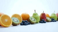 Fresh colorful fruits arranged in row on white background including orange, kiwi, blueberries, pears and apples for healthy eating and nutrition concepts.