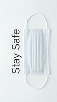 Disposable medical face mask with Stay Safe text on white background, top view health protection concept for social media.