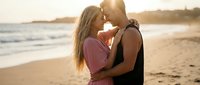 Young couple embracing on beach at sunset, romantic moment by ocean waves. Perfect for love, relationship, vacation and travel concepts.