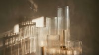 Elegant ribbed glass candle holders with golden bases casting warm light patterns on a textured wall, luxury home decor interior styling.
