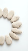 Smooth beige pebbles arranged in curved pattern on white background, isolated stones for wellness, spa, meditation, and design projects.