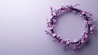 Delicate pink cherry blossom wreath on soft purple background. Floral spring arrangement in circular shape with copy space for seasonal designs.
