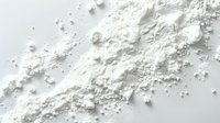 Pure white powder scattered on light surface, creating delicate texture with small particles and dust forming abstract pattern. Macro photography on clean background.