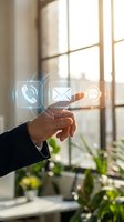 Business hand touching digital communication icons with phone, email and chat symbols floating in modern office environment with natural sunlight.