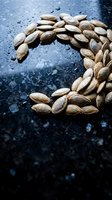 Raw almonds arranged in crescent moon shape on dark wet surface with water droplets for culinary and healthy eating concepts.