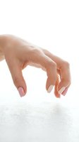 Female hand with manicured nails reaching down in grasping motion isolated on white background for design projects and commercial use.