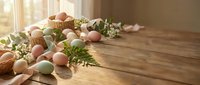 Colorful Easter eggs scattered on rustic wooden table with spring flowers and natural decorations for holiday celebration and seasonal design projects.