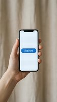 Hand holding smartphone with blue Buy Now button on screen, concept of mobile shopping, e-commerce and online retail on neutral background.