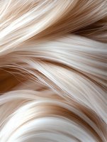 Flowing platinum blonde hair strands in macro shot showing smooth, silky texture and natural movement against neutral background, suitable for beauty and haircare advertising.