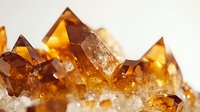 Amber-colored crystal formations with sharp geometric shapes and translucent edges against light background, showcasing natural mineral growth patterns and textures.
