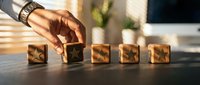 Business professional arranging wooden blocks with checkmarks on desk, representing task completion, goal achievement and project management success.