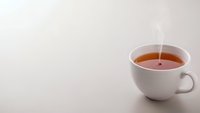 White ceramic cup with hot steaming tea on clean minimalist background for beverage and relaxation concepts.