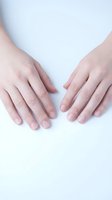 Two female hands with natural manicured nails positioned on clean white surface showing healthy skin and fingernails for beauty and skincare concepts.