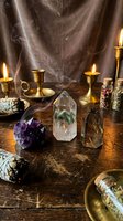 Mystical altar setup with healing crystals, burning candles, sage bundles and brass candlesticks creating atmospheric spiritual meditation space for wellness rituals.
