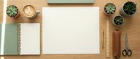 Minimalist workspace flat lay with blank paper, coffee cup, succulents, notebooks and wooden stationery on natural wood desk for creative projects.