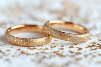 Golden wedding rings with textured sparkle finish on white lace background, romantic symbol of marriage and eternal love, luxury jewelry photography.