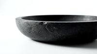 Dark rustic stone bowl with textured surface on white background, showcasing natural material craftsmanship for food, decor, and lifestyle concepts.