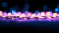 Glowing fairy lights creating magical bokeh effect with purple and blue blurred background, decorative string illumination for festive holiday atmosphere.