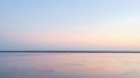 Serene ocean horizon at sunset with soft pastel sky colors reflecting on calm water surface creating peaceful seascape for meditation and relaxation themes.