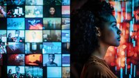 Young African American woman in profile against video wall background with multiple screens displaying diverse content, illuminated by vibrant neon lighting.