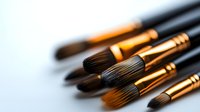 Professional makeup brushes with golden ferrules and dark bristles arranged diagonally on light background, close-up view for cosmetic and beauty industry use.