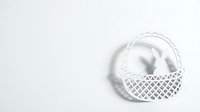 White paper cut Easter basket with eggs on light background for spring holiday greeting cards and decorations.