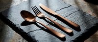 Wooden handle flatware set with spoon, fork, and knife arranged on slate surface, suitable for dining, tableware design, and restaurant branding.