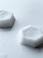 White hexagonal soap bars with foam on wet surface, minimalist bathroom accessories for skincare and hygiene routines.