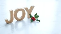 Wooden JOY letters with holly berries on white marble surface, festive Christmas holiday decoration with copy space for seasonal greeting cards.