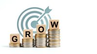 Business growth concept with stacked coins forming ascending bars and target with arrow, representing financial success and investment strategy goals.
