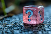 Pink translucent dice with blue question mark symbol on wet surface showing mystery and uncertainty concept in gaming and decision making. Macro photography.