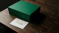 Green gift box with thank you card on dark wooden table, elegant presentation for holidays, corporate gifting, and special occasions.