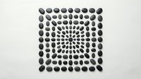 Dark gray oval stones arranged in geometric square pattern creating optical illusion effect on white background for modern design projects.