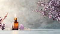 Aromatherapy essential oil bottle with amethyst crystal and cherry blossom branch on soft gray background, creating serene wellness atmosphere.