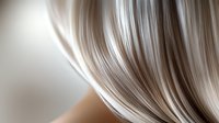 Smooth flowing platinum blonde hair strands in macro shot against blurred background, showing silky texture and natural shine. Professional hairstyling and beauty concept.