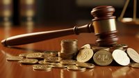 Wooden judge gavel with golden coins on desk representing legal fees, financial litigation, court costs, bankruptcy proceedings, and monetary justice concepts.