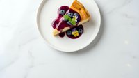 Gourmet dessert with berry compote and pastry garnish on white plate, elegant restaurant plating for culinary photography and food styling projects.