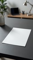 Blank white paper sheet on modern office desk with laptop and lamp in blurred background for business presentations and document templates.