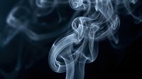 Delicate white smoke swirls gracefully against a dark background, creating an abstract, ethereal effect with flowing curves and soft textures.