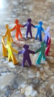 Colorful paper cutout figures holding hands in circle formation on marble surface, representing unity, teamwork and diversity in community or workplace setting.