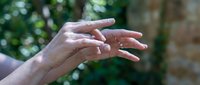 Caucasian woman hands with elegant manicured nails gesturing expressively outdoors against natural green foliage background for communication concepts.