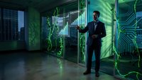 Professional businessman in dark suit interacting with futuristic holographic interface displaying green digital data and circuit patterns in modern office.