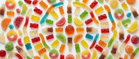 Colorful assorted gummy candies and jellies scattered on white background creating vibrant sweet treat pattern for confectionery and dessert designs.