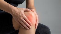 Woman holding inflamed knee joint showing pain and discomfort from arthritis or sports injury requiring medical treatment and physiotherapy care.