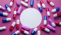 Colorful pharmaceutical capsules arranged in circular pattern around white blank space on pink background. Medical concept with red, blue and purple pills.