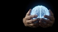 Human hands holding glowing brain against dark background, representing intelligence, knowledge, mental health, neurology, psychology, innovation, creativity, and medical science concepts.