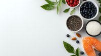 Fresh salmon fillet with superfoods including chia seeds, coconut flakes, berries, nuts and green leaves arranged on white background. Great for healthy eating blogs.